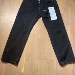 Svarta jeans från Weekday - Säljer ett par svarta jeans från Weekday i modellen 'Space'. De är tillverkade av ekologisk och återvunnen bomullsblandning. Jeansen har en balanserad straight passform och är perfekta för både vardag och fest. De är i nyskick och har en klassisk design med fem fickor och knappgylf.