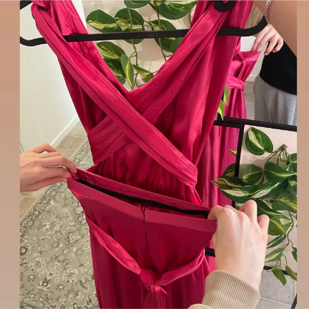 Fantastisk rosa långklänning i satin med en elegant v-ringning och inbyggd bh. Klänningen har en vacker omlott-detalj i midjan som ger en smickrande siluett. Perfekt för festliga tillfällen som nyår eller bal. *skräddarsydd* . Mekot.