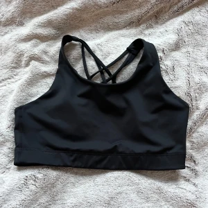 Svart sporttopp med korsade band - Snygg svart sporttopp med korsade band i ryggen. Perfekt för träning och ger bra stöd. Tillverkad i ett mjukt och stretchigt material för optimal komfort🤍💅🏼