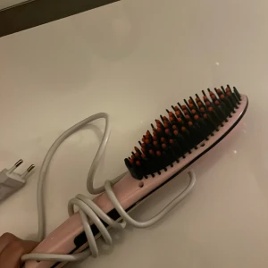 Fast hair straightener  - Säljer en fast hair straightner hårborste med sladd, märkt 'Fast Hair Straightener'. Perfekt för att snabbt och enkelt styla håret. Borsten har svarta och röda borstpiggar och en EU-kontakt.