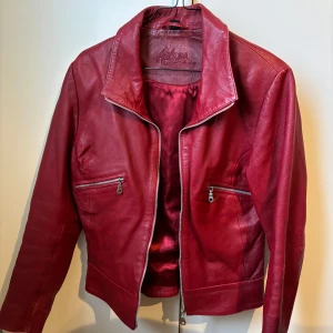 Röd skinnjacka från Auluna Leather Company - Snygg röd skinnjacka från Auluna leather company i äkta skinn med dragkedja framtill och två dragkedjefickor. Otroligt fin röd färg, storlek S. Säljes pga för liten. 