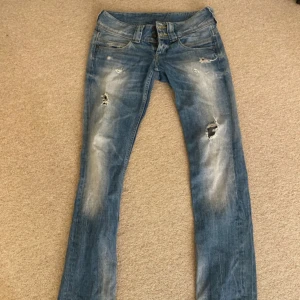 Blå Lågmidjade jeans från Pepe Jeans - Snygga blå jeans från Pepe Jeans med slitna detaljer! Tillverkade i 100% bomull för en bekväm känsla. Väldigt Lågmidjade!
