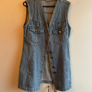 Jeansväst med knappar - Snygg jeansväst från Jep’s i en klassisk blå denimfärg. Västen har en v-ringad design med knappar framtill och två bröstfickor med knappdetaljer. Perfekt för en avslappnad stil.