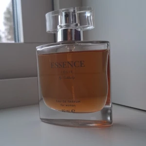 Essence Jolie Eau de Parfum - Elegant och feminin Eau de Parfum för kvinnor från Essence Jolie. Flaskan är stilren och genomskinlig med en fyrkantig form och ett klart lock. Innehåller ungefär 45 ml av en varm och inbjudande doft.Hittade inte förpackningen för parfymen därför säljer jag den för billigare.