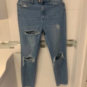 Blå jeans med slitningar från Missguided - Snygga blå jeans från Missguided med slitningar på knäna och låren. De har en klassisk femficksdesign och knappgylf. Perfekta för en avslappnad stil.