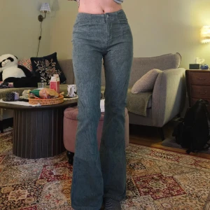 Gröna manchesterbyxor från Lucky Brand - Snygga gröna manchesterbyxor från Lucky Brand med hög midja och bootcut-stil. Byxorna har dragkedja och knappar framtill, vilket ger en klassisk look. Perfekta för en trendig och bekväm stil. Midjemått 33-34 cm, innerbenslängd 78 cm