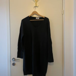 Klänning från I Say - Elegant mörkgrå klänning från I Say med v-ringning och långa ärmar. Klänningen har en enkel och tidlös design som passar till många tillfällen. Hittar ingen storlek men har burits av person med storlek M/L