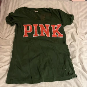 Grön t-shirt från Victoria's Secret PINK - Snygg grön t-shirt från Victoria's Secret PINK med stort rosa tryck fram och siffrorna 86 i zebra- och leopardmönster på baksidan. Perfekt för en avslappnad stil.