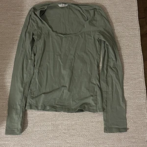 Grön långärmad topp - Säljer en stilren grön långärmad topp med rund halsringning. Perfekt för en avslappnad look. Passar bra till jeans eller kjol.