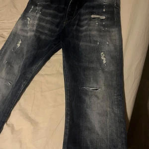Blå jeans från Elias Rumelis - Snygga blå jeans från Elias Rumelis med slitna detaljer och en avslappnad passform. Perfekta för en cool och avslappnad stil. De har en klassisk femficksdesign och är tillverkade i denim.