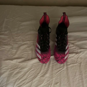  fotbollsskor från Adidas - Snygga fotbollsskor från Adidas i svart och rosa med ett unikt mönster. Skorna har snörning och är perfekta för fotbollsplanen. De har en robust sula med dobbar för bra grepp spel på konstgräs och vanlig gräs aldrig använda pris kan sänkas och diskuteras 