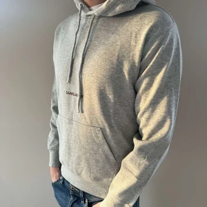 Grå hoodie från Saint Laurent - Säljer en stilren grå hoodie från Saint Laurent då den börjar bli för liten. Hoodien är i storlek S men passar även större XS. Den är använd max 7 ggr och tvättats en gång vilket var innnan jah la ut den här på Plick! Hör av dig vid funderingar eller frågor!