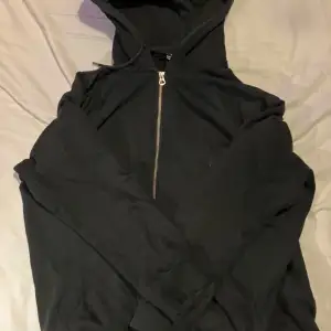 Säljer en svart hoodie från Weekday med dragkedja framtill. Perfekt för en avslappnad stil med sin klassiska design och bekväma passform. Huvan ger extra mysfaktor och skydd mot kyliga dagar.
