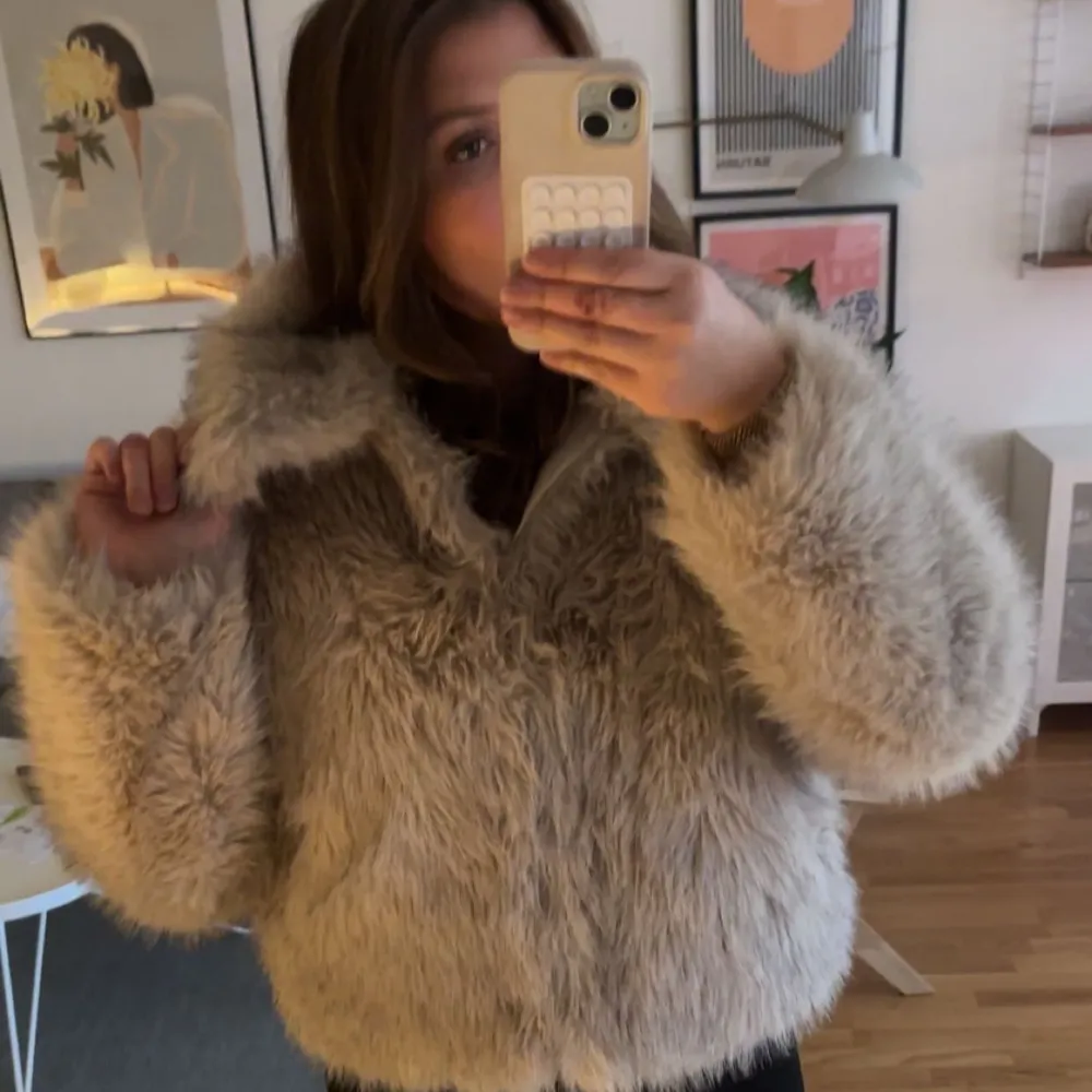 Säljer en fluffig och trendig beige pälsjacka med långärmad design. Jackan har en oversized passform och är perfekt för kyligare dagar. Den ger en lyxig känsla och är lätt att matcha med olika outfits.. Takit.