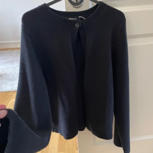 Svart kofta  - Snygg och stilren svart kofta. Den har en enkel knapp framtill och långa ärmar. 