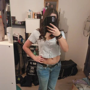 Ljusblå croppad blus - Säljer en ljusblå croppad blus med korta ärmar och knappar framtill. Perfekt för en avslappnad stil.