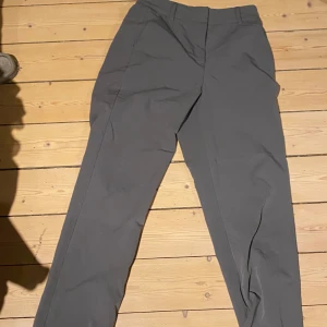 Grå kostymbyxor från Vero Moda - Snygga grå kostymbyxor från Vero Moda med en klassisk design. Perfekta för en stilren look. Byxorna har en rak passform och är tillverkade i ett bekvämt material.