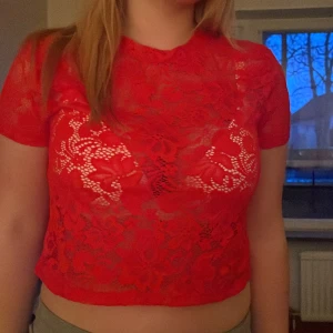 Röd spets topp - Snygg röd spets topp med korta ärmar och croppad design. Perfekt för en kväll ute eller en festlig tillställning. Toppen har ett vackert blommönster och är tillverkad i ett lätt och luftigt material.