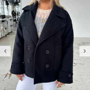 Design By Si Kappa - Snygg svart kappa med dubbelknäppning och breda slag. Jackan har långa ärmar och en klassisk look som funkar till det mesta. Använd fåtal gånger under hösten, köpt förra hösten. Skriv för fler bilder🥰