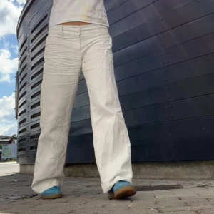 Vita linnebyxor - Snygga vita linnebyxor med en avslappnad passform. Perfekta för varma dagar med sin luftiga design. Byxorna har en rak stil och är lågmidjade för en bekväm känsla. Kan ha slitningar längst ner.