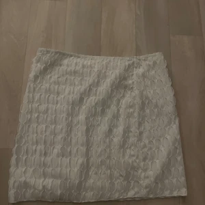 Vit kjol med struktur - Snygg vit kjol med unik struktur som ger en modern touch. Perfekt för att lyfta vilken outfit som helst. Enkel och stilren design.