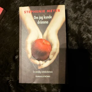 Om jag kunde drömma - Boken 'Om jag kunde drömma' av Stephenie Meyer, utgiven av B. Wahlströms. Omslaget visar två händer som håller ett rött äpple mot en mörk bakgrund. En omöjlig kärlekshistoria.