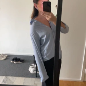 Ljusblå blus - Säljer en ljusblå blus med v-ringning och långa ärmar. Perfekt för en stilren och avslappnad är look. Blusen har en enkel design som gör den lätt att matcha med olika outfits.