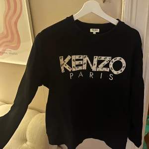 Svart tröja från Kenzo - Den är för herr men jag har använd den som tjej också och sitter fint på. Säljer en svart tröja från Kenzo med stort tryck av märkesnamnet på framsidan. Tröjan har långa ärmar och en rund halsringning. Perfekt för en stilren look. Köpt för lite mer än 2000 kr 