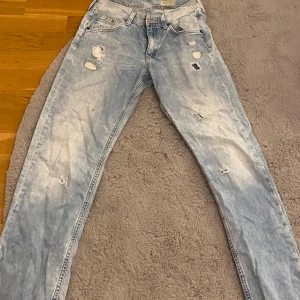 Ljusa jeans med slitningar - Ljusblå jeans med coola slitningar framtill. De har en loose fit och är lågmidjade.