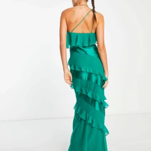 Grön balklänning med volanger och silke - Grön balklänning från ASOS, köpt på vinted och varit använd en gång av tidigare ägare. Har bara provat den själv, men säljer då jag ska ha en annan balklänning. Fint skick och inga defekter vad jag hittat! Når precis över marken på mig som är 179🫶🏼 Pris kan diskuteras!!!