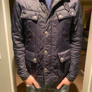 Mörkblå quiltad jacka från Barbour - Säljer en snygg mörkblå quiltad jacka från Barbour. Jackan har en unik design. Storleken är i S Pris 650        Jackan är i nyskick knappt använd.