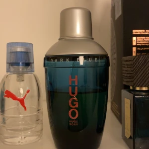 Hugo Boss Dark Blue Parfym - Säljer en elegant Hugo Boss Dark Blue parfym i en stilren flaska med mörkblått glas och silverfärgat lock. Flaskan har en modern design med märkets logotyp i rött. Perfekt för den som vill ha en sofistikerad doft. Cirka 50 ml kvar