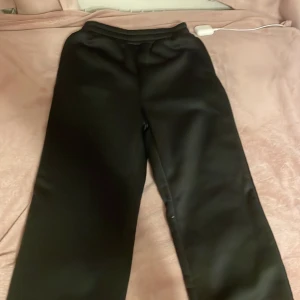 Svarta mjukisbyxor - Har aldrig haft dom fick fel storlek av min kusin. Säljer ett par svarta mjukisbyxor med elastisk midja. Perfekta för en avslappnad stil och bekväma att bära. Byxorna har en enkel design utan extra detaljer.
