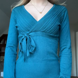 Omlottopp med knytband - Snygg mörkgrön/turkos/blå omlottopp med ribbade detaljer och knytband i midjan. Mycket bra skick💗Passar S-M