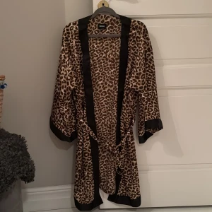 Leopardmönstrad kimono från Bubbleroom - Snygg leopardmönstrad kimono från Bubbleroom med svarta kanter och knytband i midjan. Perfekt för en chic och avslappnad look. 🐆✨