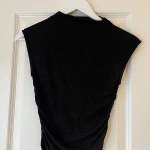 Svart ärmlös topp från Gina Tricot - Säljer en stilren svart ärmlös topp från Gina Tricot i storlek XS. Toppen har en tight passform och är tillverkad i ett mjukt material som sitter skönt mot kroppen.💗