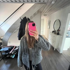 Grå quiltad jacka zara - Säljer en snygg grå quiltad jacka med dragkedja och hög krage. Jackan har två stora fickor framtill och en justerbar dragsko i nederkant. Perfekt för kyligare dagar.