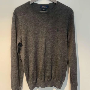 Merinoull Tröja Polo Ralph Lauren - Säljer en stilren grå tröja från Polo Ralph Lauren i merinoull. Tröjan har en slim passform och långa ärmar, perfekt för en elegant look. Den är diskret dekorerad med en liten broderad logotyp på bröstet. Tröjan är i Merinoull , står L men krympt till S. Pris går alltid att diskutera! ✅