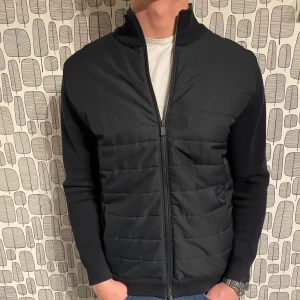 Svart jacka från Massimo Dutti - Snygg svart jacka från Massimo Dutti med dragkedja framtill. Jackan har en quiltad design på framsidan och långa ärmar. Perfekt för en stilren look.