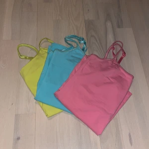  Linne från The Essentials - Säljer tre färgglada linnen från The Essentials i ekologisk bomull. Färgerna är gul, blå och rosa. Perfekta för sommaren med smala axelband och en enkel design. Passar bra till både jeans och shorts! (Innanför linnet runt bysten är det som ett extra tyg) 100kr för alla tre! 