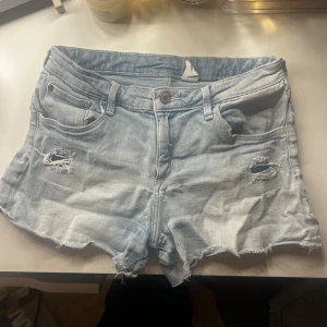 Ljusblåa denimshorts med lite slitningar - Jättefina jeansshorts med lite slitningar på framsidan av shortsen, sparsamt använda