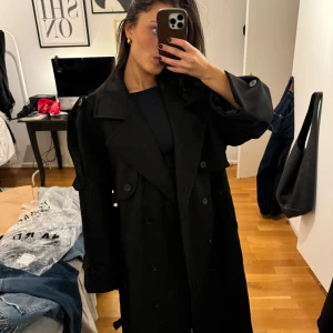 Svart trenchcoat - Säljer denna stilrena kappa från Josefin hj x nakd, säljer då jag köpt två likadana och inte hann lämna tillbaka ena! Prislappen sitter kvar! (Nypris 1600kr) 