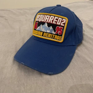 Blå DSquared2 keps - En snygg blå DSquared2 keps med broderad text i fint skick, perfekt för en casual look eller att lyfta din outfit. Kepsen har en justerbar passform.