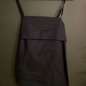 Svart Topp - Snygg svart topp med axelband, perfekt basplagg. Den har en enkel och elegant design som gör den lätt att matcha med olika accessoarer. Toppen är i bra skick och passar perfekt för sommar. Oanvänd och jag tror att kappen fortfarande sitter kvar.