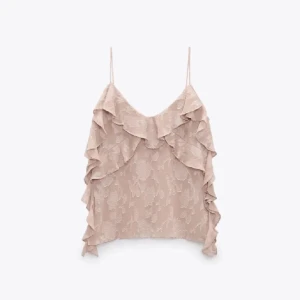 Rosa volangtopp - Säljer en superfin beige topp med volanger och tunna axelband. Perfekt för sommardagar eller en festlig kväll. Toppen har ett diskret blommönster som ger en romantisk touch. Passar bra till både jeans och kjol!