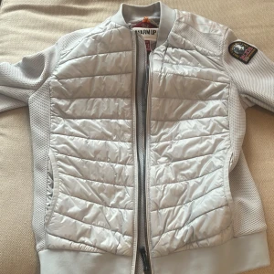 Grå hybrid jacka från Parajumpers - Säljer en snygg grå jacka från Parajumpers i storlek Y-S. Jackan har en quiltad design med dragkedja och en cool patch på ärmen. Perfekt för höst och vår när du vill hålla dig varm och stilren. För de som undrar så har inte hybrid jackan den gula taggen! Plagget är perfekt för dig som vill vara riktigt grish! Jackan är aldrig använd då jag fått en storlek för liten av min Farmor! 