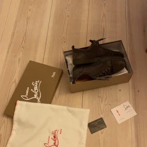  Christian Louboutin Grå - Säljer ett par snygga grå sneakers från Christian Louboutin i mocka. ☕️ Skorna har den ikoniska röda sulan och snörning framtill. De är i mycket bra skick och kommer med originalförpackning och dustbag. Perfekta för både vardag och fest!🎉 Såklart tvättar jag dem innan dem skickas! Storlek 41 Tyvvär så är kvittot borttappat😓🫤