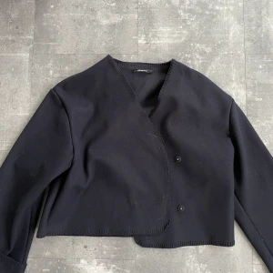 Svart kappa från Gina Tricot - Snygg blå-svart kavaj med v-ringning och knappar framtill. Den har en croppad stil och långa ärmar, perfekt för både vardag och fest. Enkel men stilren design som passar till det mesta😘💄💕