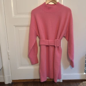 Rosa stickad klänning från & Other Stories - Superfin rosa stickad klänning från & Other Stories i storlek S. Den har långa ärmar och ett matchande bälte i midjan för en snygg siluett. Perfekt för höst och vinter, både mysig och stilren! Bältet kan tas loss! Endast testad.