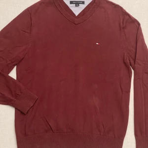 Vinröd sweatshirt från Tommy Hilfiger - Säljer en snygg vinröd sweatshirt från Tommy Hilfiger i mycket bra skick. Perfekt för höst och vinter, och den lilla loggan på bröstet ger en stilren touch. Passar både till vardags och lite finare tillfällen.